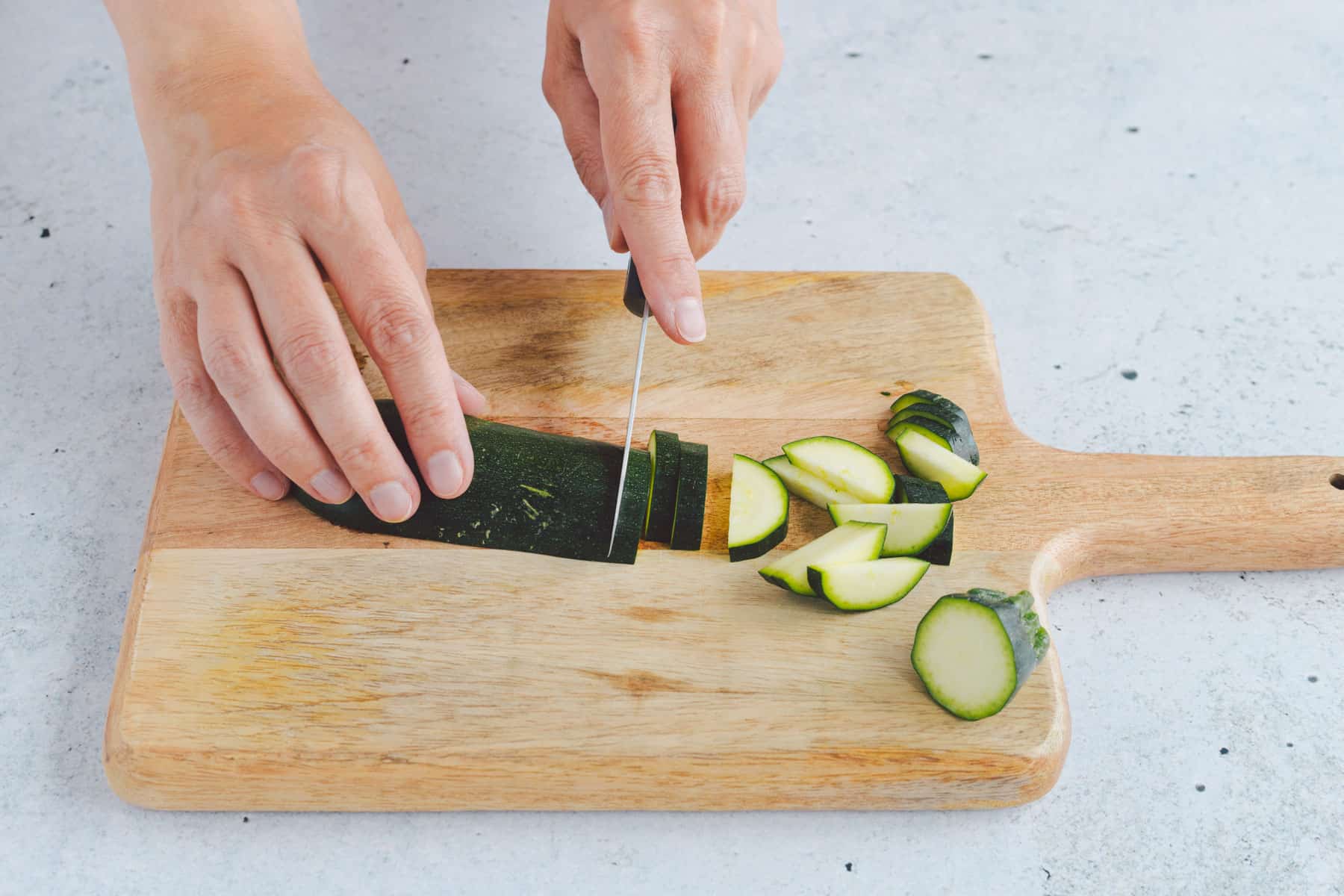 Zucchini werden auf einem Holzbrett für Zucchini-Pasta in Scheiben geschnitten.