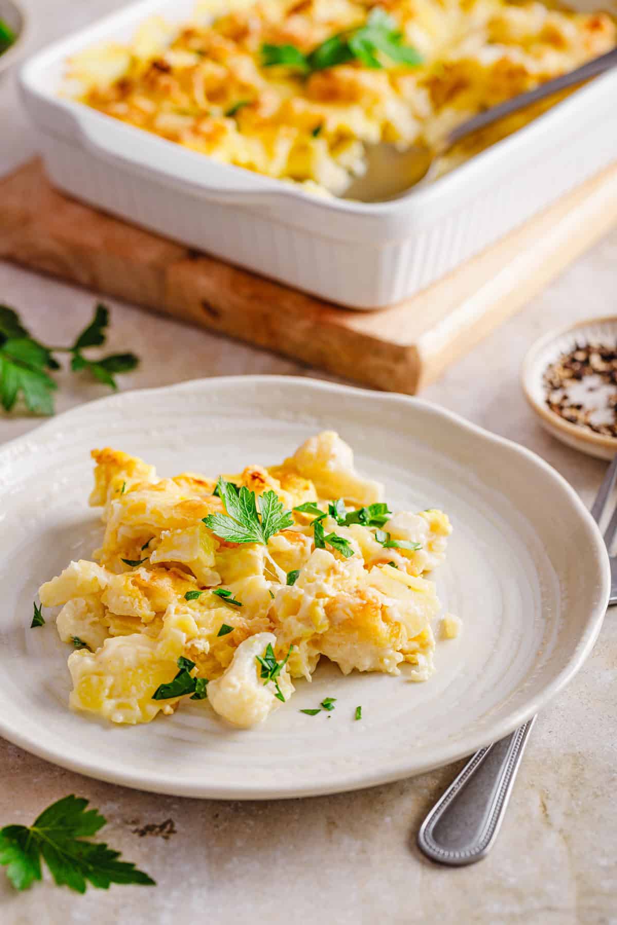 Eine Portion Kartoffel-Blumenkohl-Gratin auf einem Teller serviert.