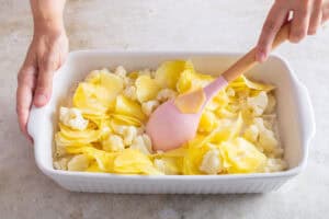 Gekochte Kartoffeln und Blumenkohl werden mit der Sauce vermengt.